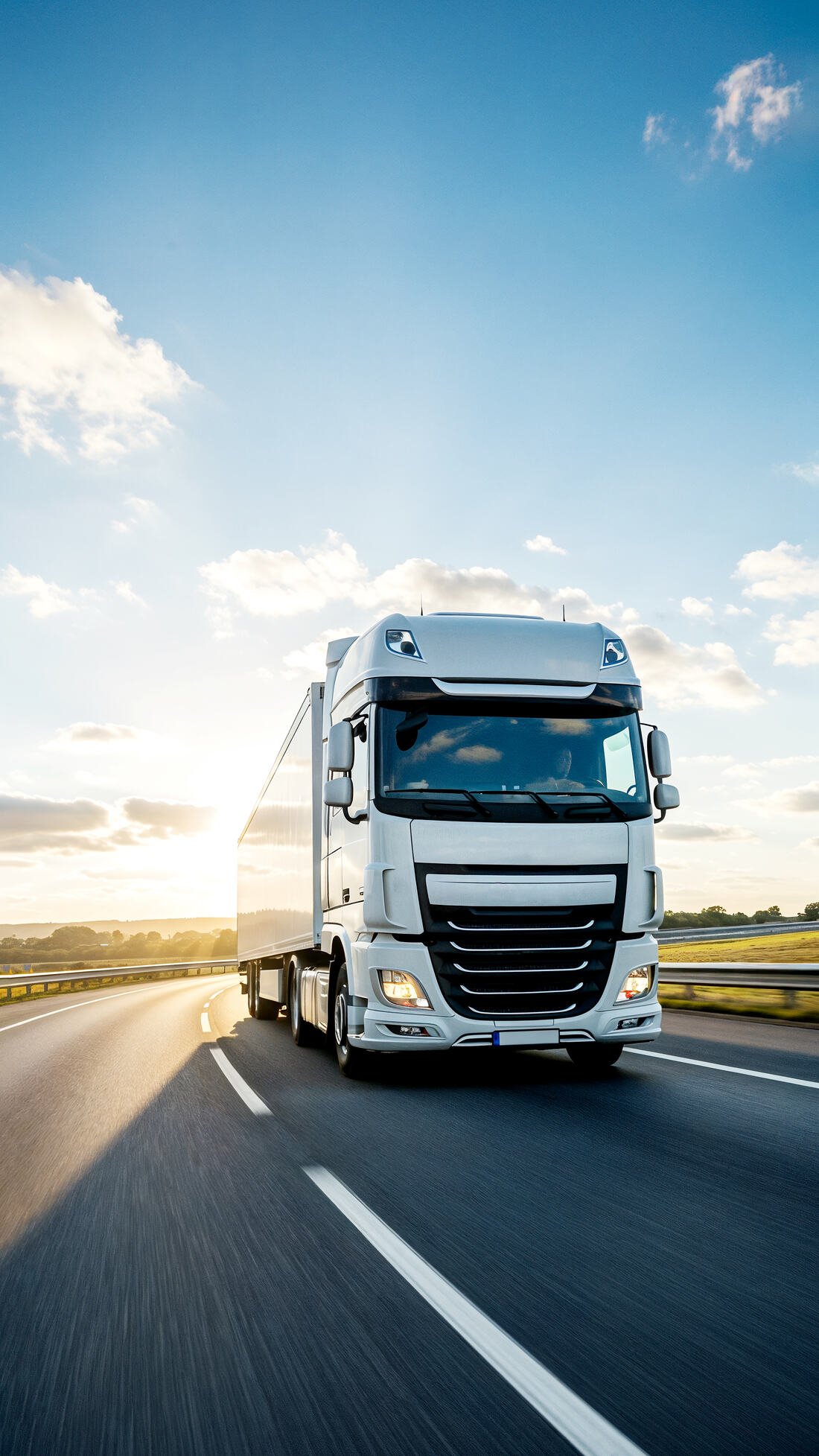 Weißer Sattelzug fährt bei Sonnenschein auf der Autobahn